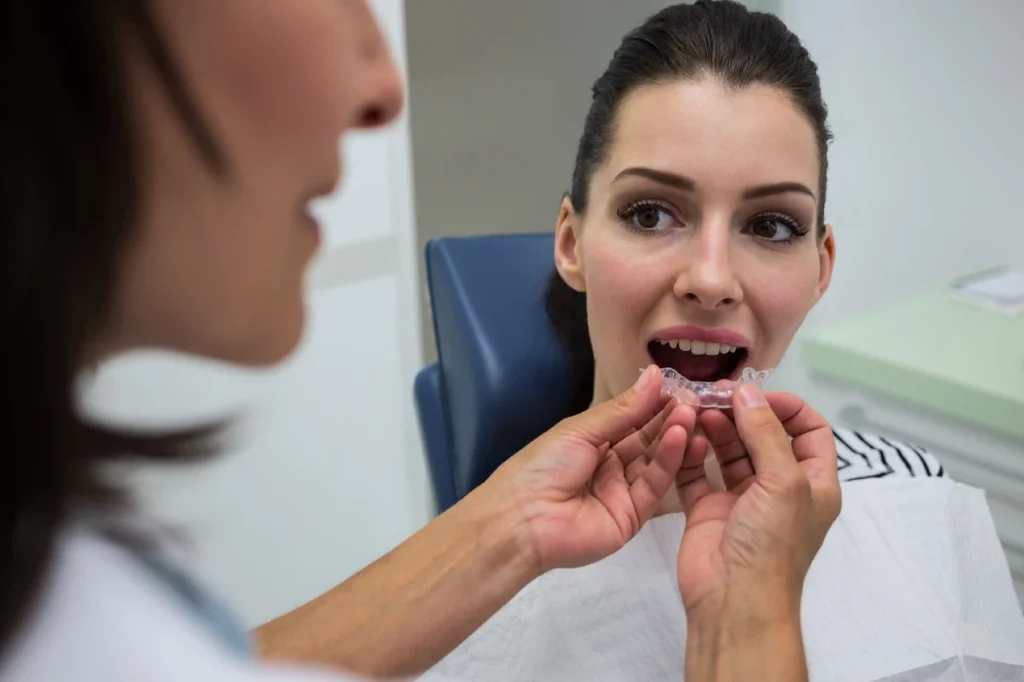 Dentist assisting a female patient in trying on a clear aligner 