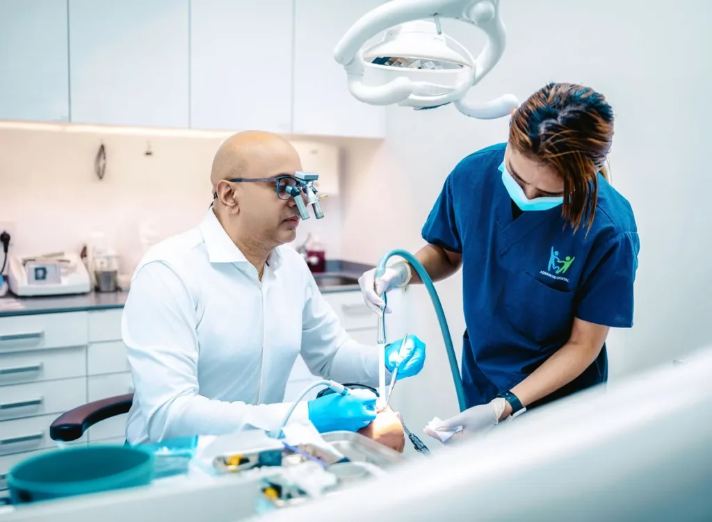 Dentist performing a root canal on a patient with an assistant
