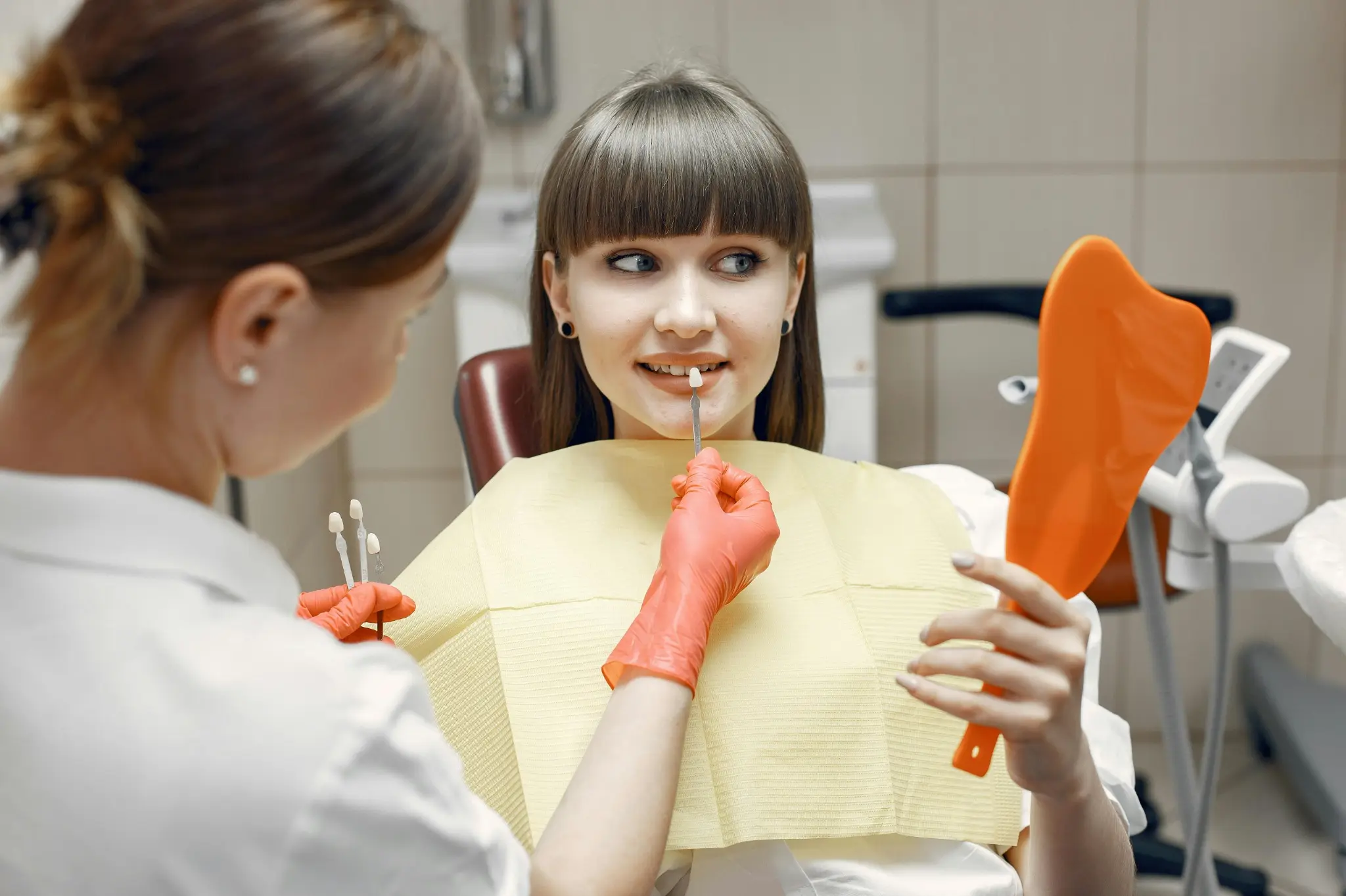 Dentist matching tooth shade for a patient during a dental checkup in a modern clinic.