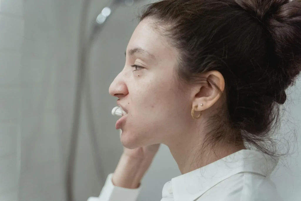 Woman brushing her teeth in a bathroom as part of a daily morning oral hygiene routine