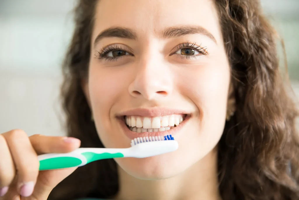 Woman brushing her teeth as part of daily oral hygiene to help prevent yellow stains